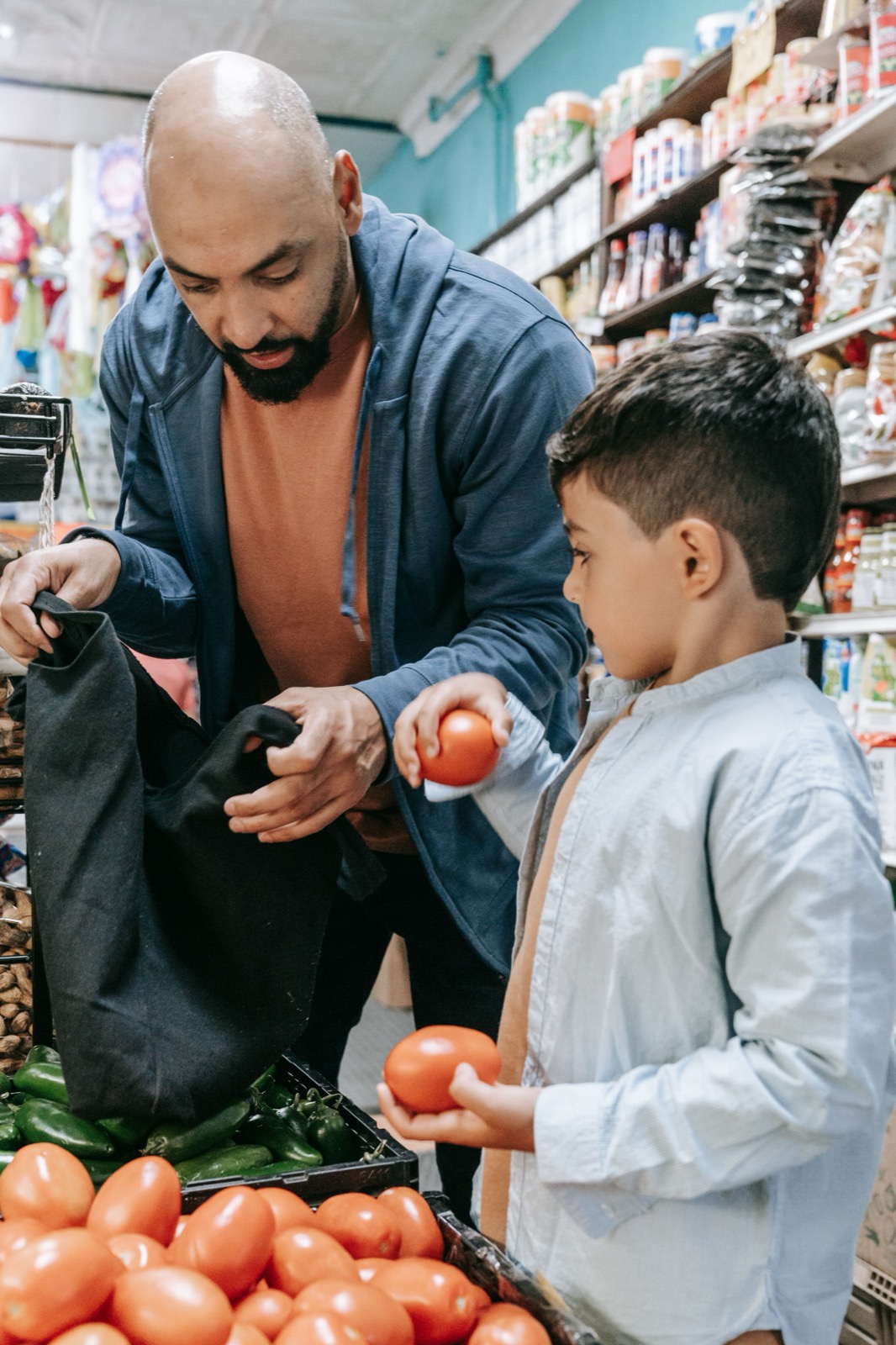 A father and son pick tomatoes in a grocery