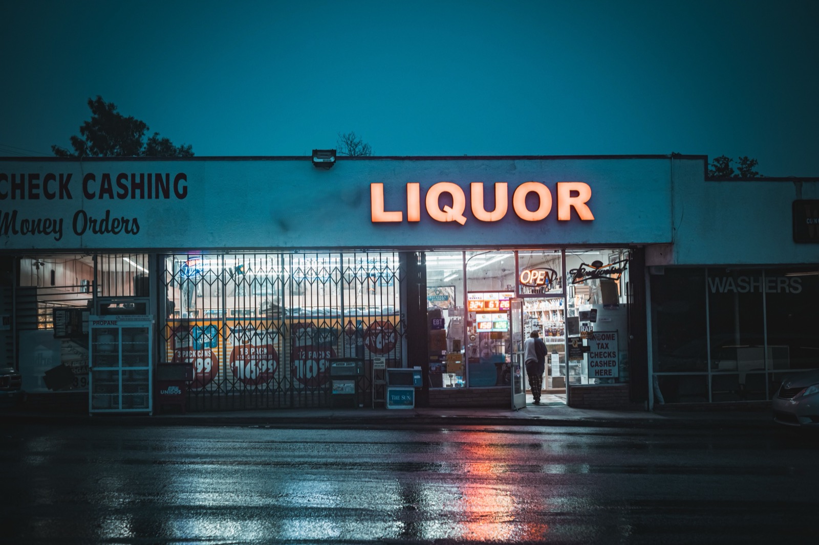 A liquor store and check cashing shop lit at night, black and white