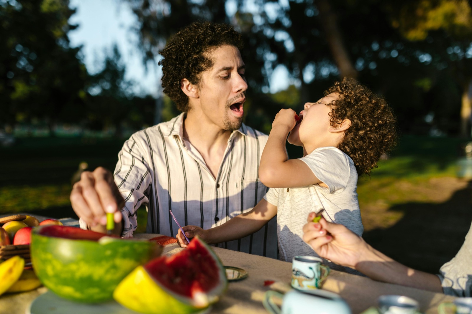 A father laughs with his child at an outdoor table