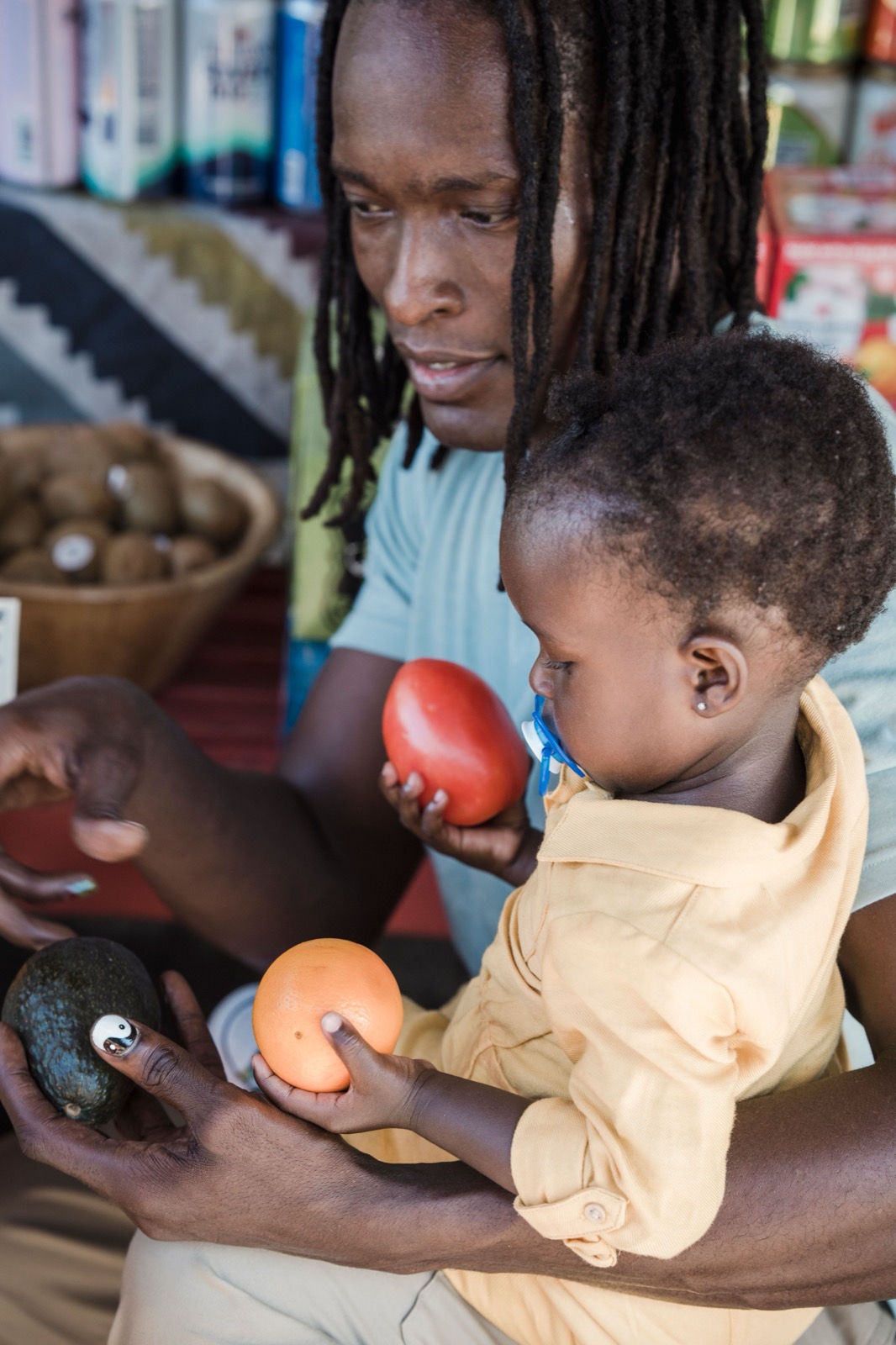 A father holds his baby, who holds an apple