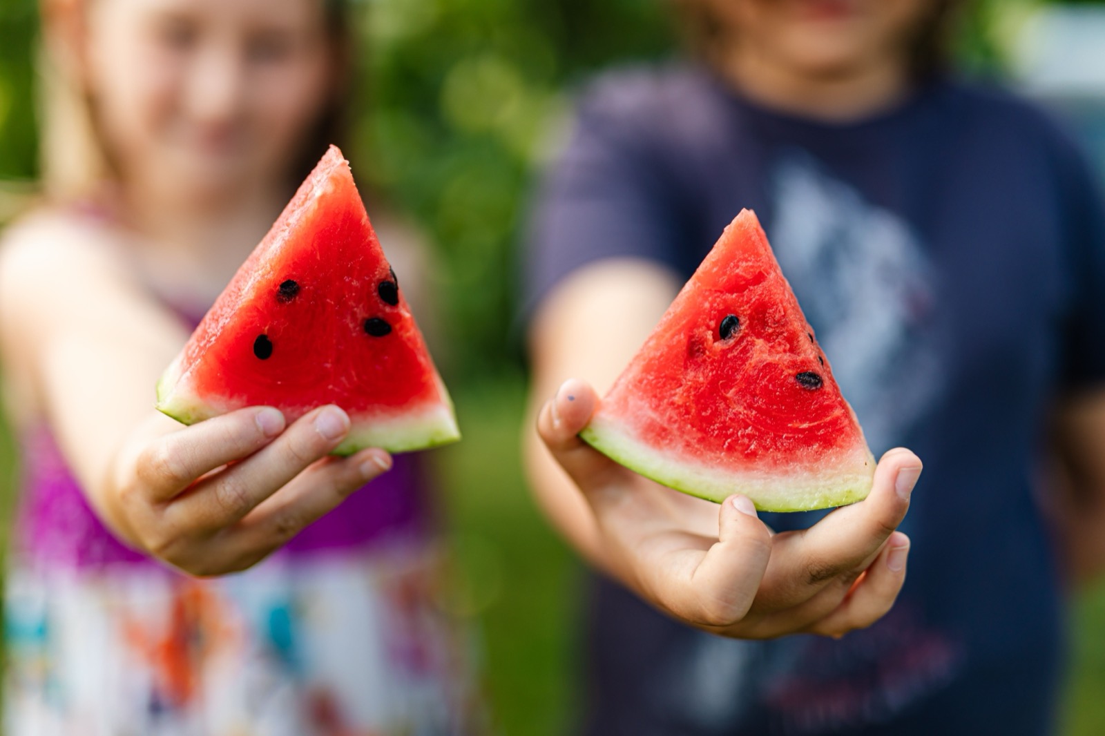 Children hold out slices of watermelon