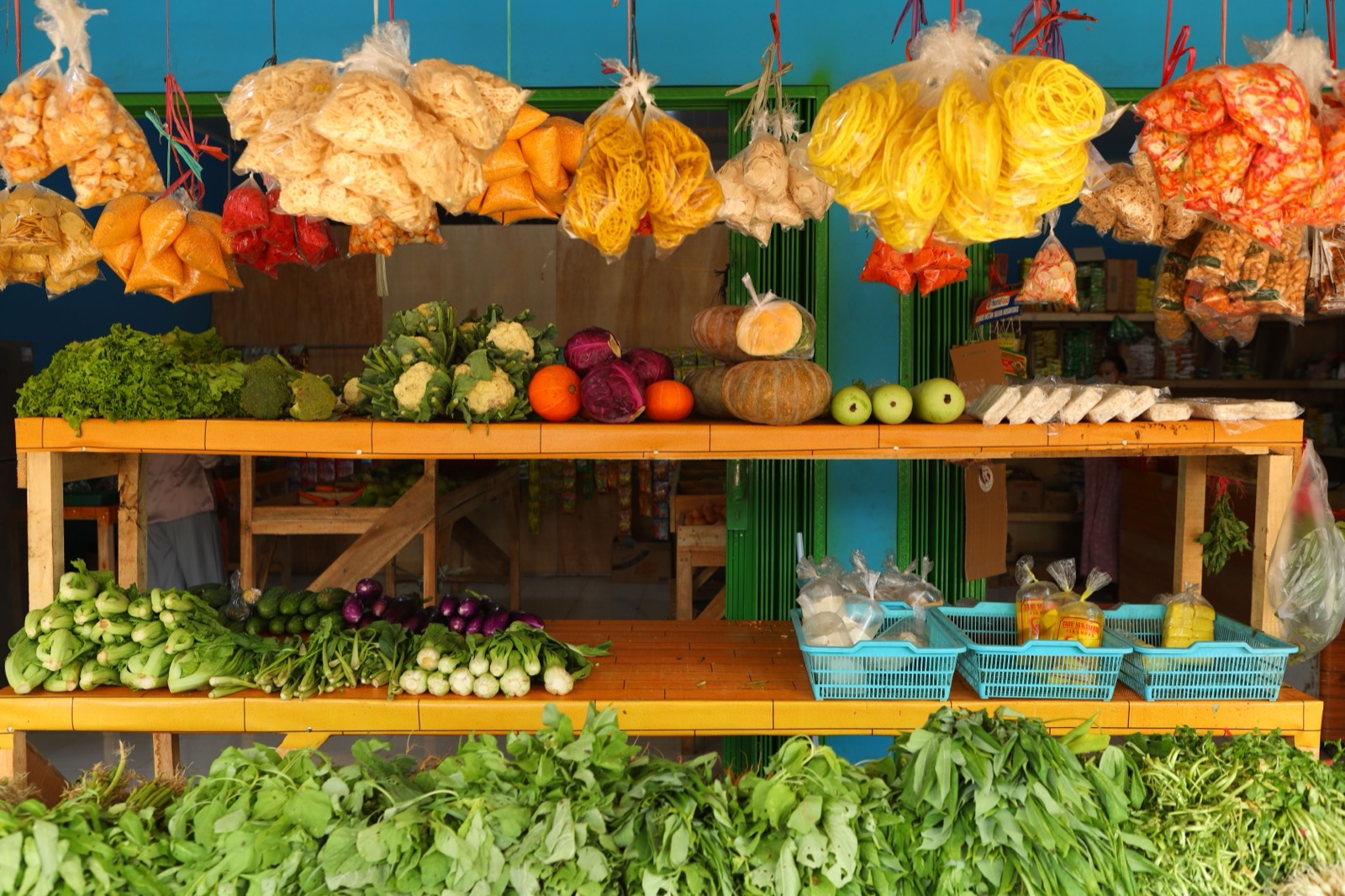 A roadside fruit stand with bananas hanging over the produce