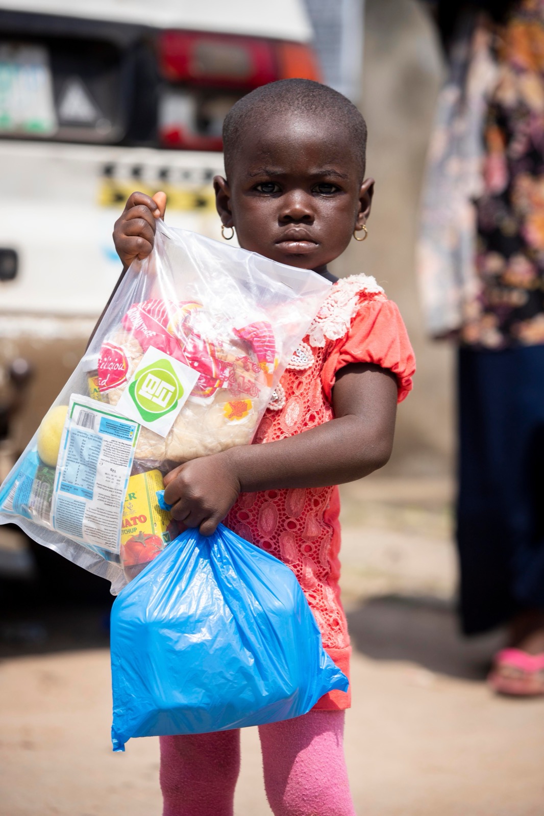 A child holds two bags of food from a food bank