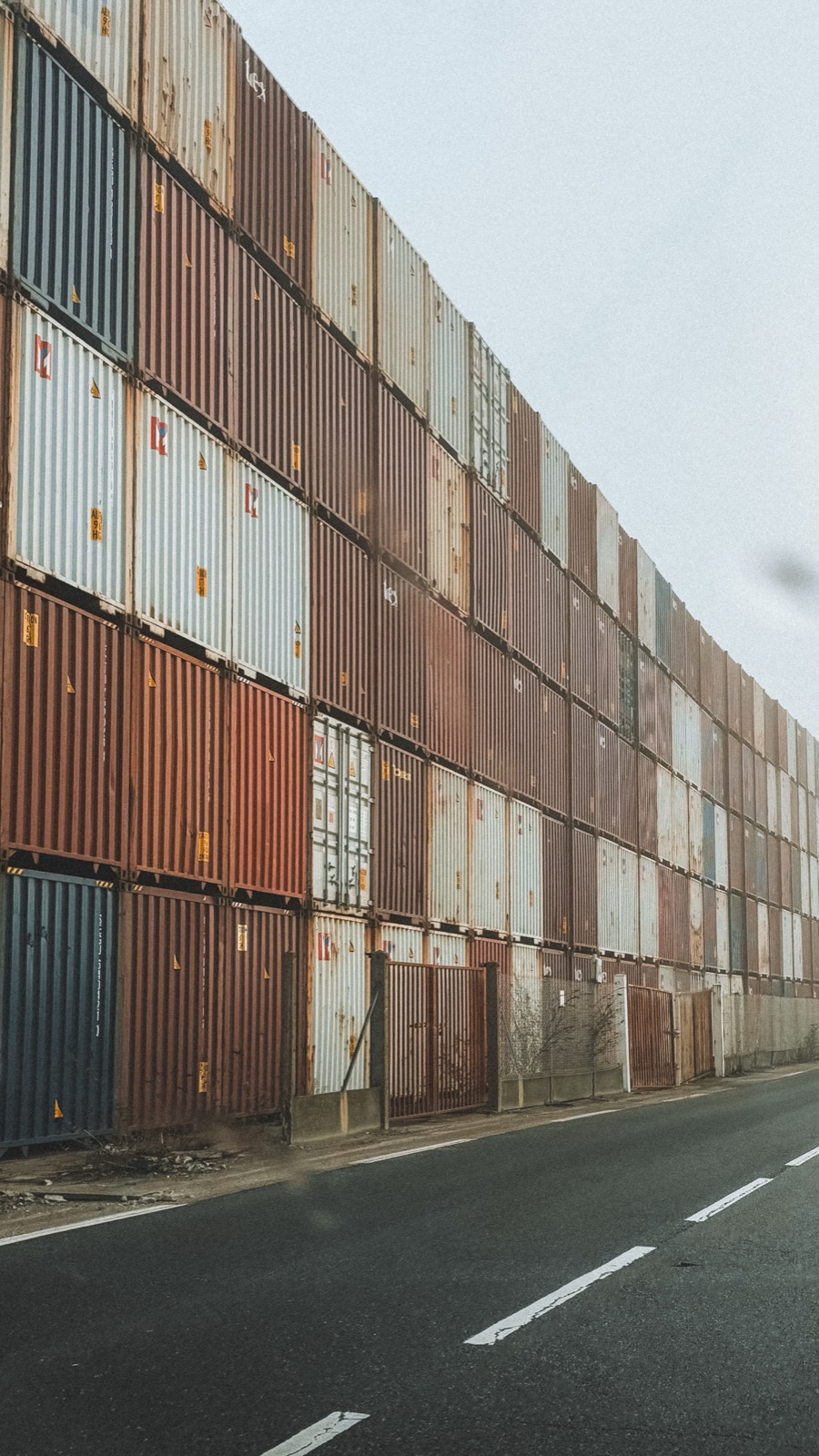 A wall of shipping containers along an empty road