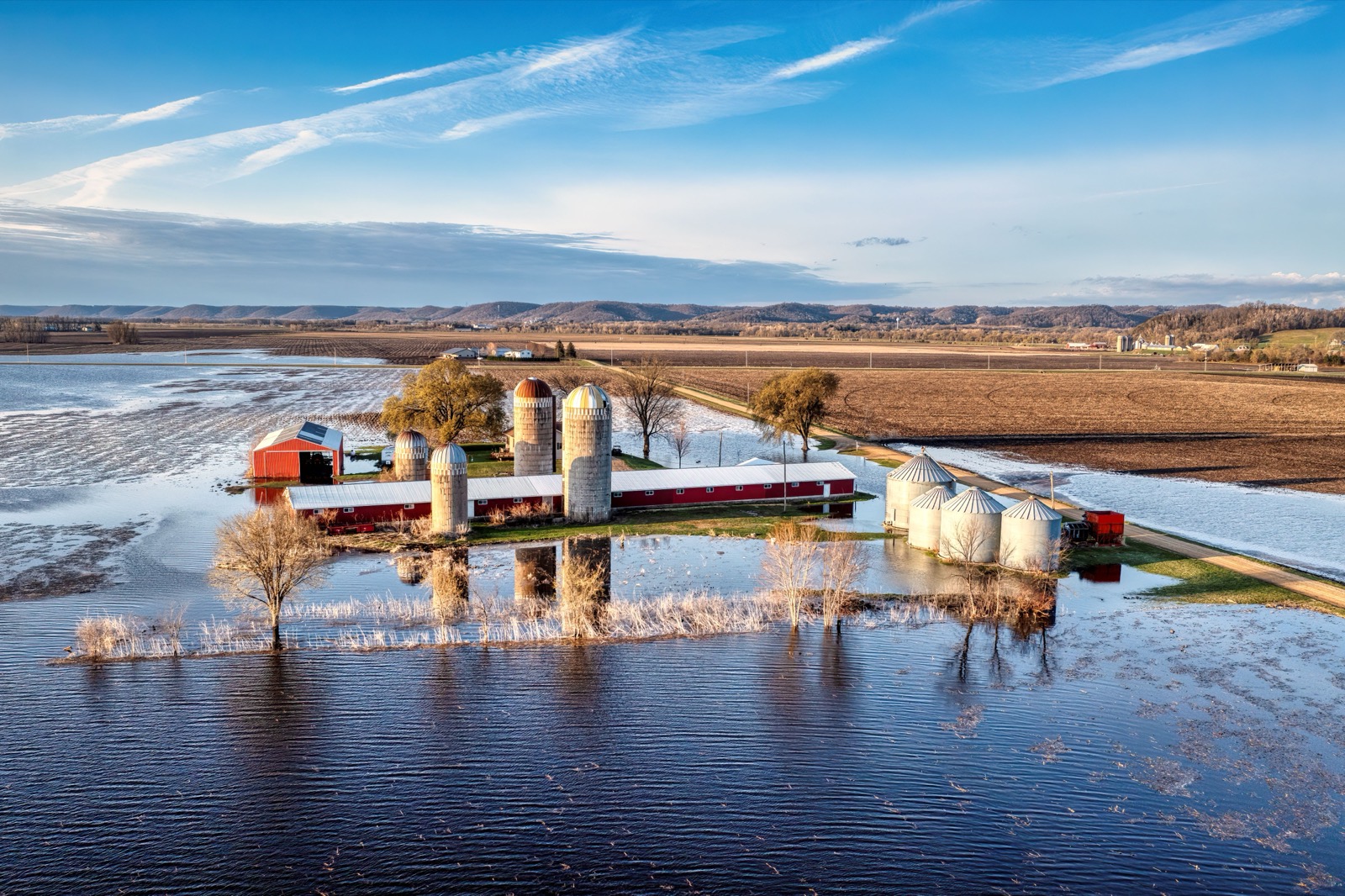Farm buildings and silos standing in floodwater